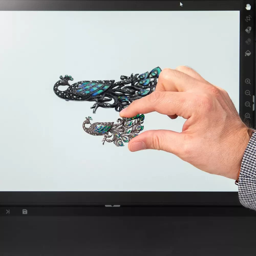 Mano sosteniendo joyería delante de una pantalla con software Orbitvu